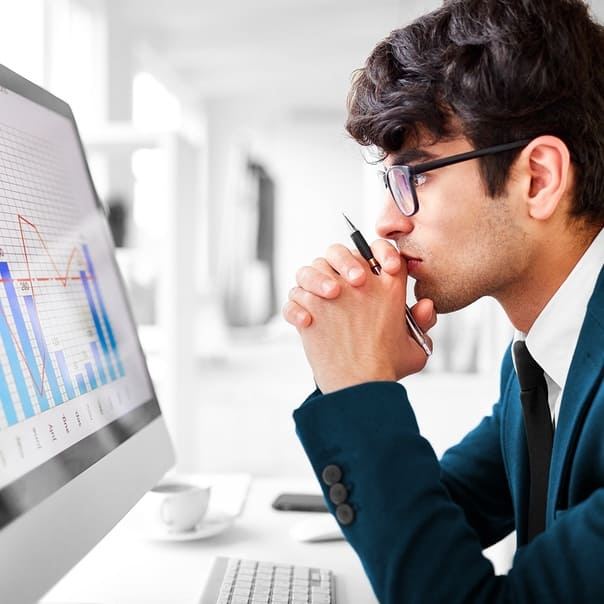 Focused young professional analyzing data on a computer screen in an office setting.